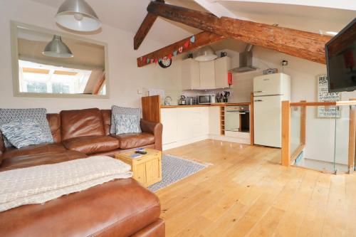 a living room with a brown leather couch and a kitchen at TOWN CENTRE contemporary cottage in Padstow
