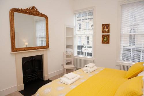 Un dormitorio con una gran cama amarilla con espejo en Stunning, 1 Bed Luxury Flat in Central Bath, en Bath