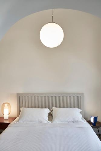 a bedroom with a large bed with a large light fixture at Old Castle Oia in Oia