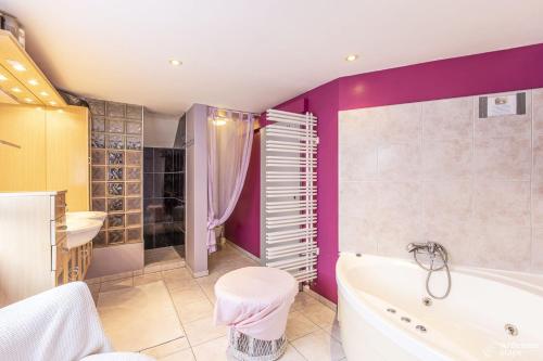 a bathroom with purple walls and a tub and a sink at Le Loft in Stoumont