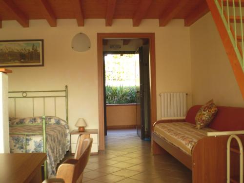 a bedroom with a bed and a couch and a window at Agriturismo Renzano garden apartments in Salò