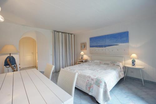 a bedroom with a bed and a table with chairs at BGItalianVacation - Ville Li Conchi in Castiadas