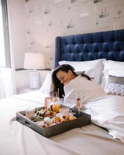 a woman laying in bed with a tray of food at Boutique Hotel & Spa Casa del Mare - Mediterraneo in Herceg-Novi