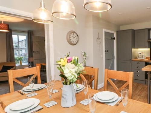 a dining room table with a vase of flowers on it at October Cottage in Barnard Castle