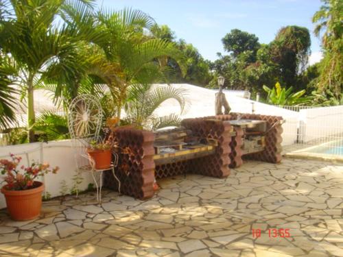 a patio with a statue of a cat sitting on a bench at Maison confortable au Bois des Nefles, 70 m² avec piscine partagée in Le Bois de Nèfles