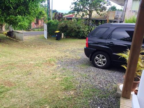 a black suv parked in the driveway of a house at Maison cosy Le Lamentin, jardin in Le Lamentin