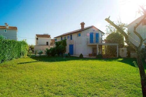 a white house with blue doors and a yard at Charming apartment in Zambratija, 44 sqm, Parking included in Zambratija