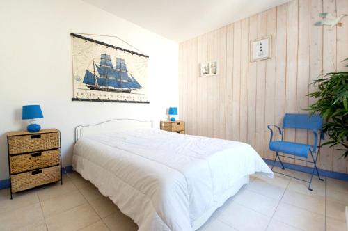 ル・ボワ・プラージュ・アン・レにあるMaison de 2 chambres a Le Bois Plage en Re a 400 m de la plage avec piscine partagee terrasse amenagee et wifiのベッドルーム(大型ベッド1台、青い椅子付)