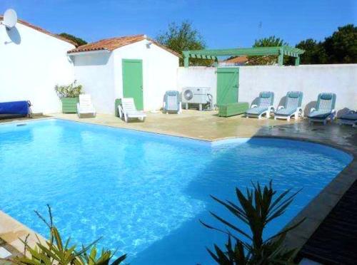 a large swimming pool with chairs in a backyard at Maison charmante à Le Bois-Plage-en-Ré avec piscine partagée in Le Bois-Plage-en-Ré