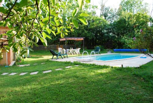 um quintal com uma piscina com cadeiras e uma mesa em Maison d'une chambre avec piscine privee jardin amenage et wifi a Sainte Alvere em Saint-Alvère