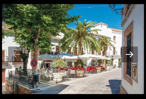 a street with tables and chairs and palm trees at 2 bedrooms chalet with lake view furnished terrace and wifi at El Gastor in El Gastor