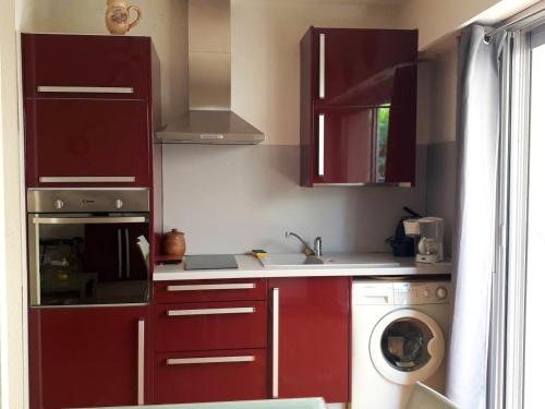 a kitchen with red cabinets and a washing machine at Appartement charmant à Saint-Aygulf avec jardin privé in Saint-Aygulf