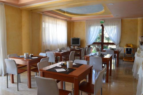 a restaurant with tables and chairs and a tv at Hotel Parco Serrone in Corato