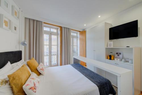 a bedroom with a white bed and a tv at Bellu Suites in Guimarães