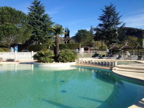 une grande piscine d'eau avec des chaises et des arbres dans l'établissement Bungalow Charmant à Sampzon 32 m² avec Vue Montagne, à Sampzon