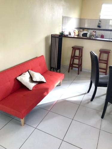 a red couch sitting in a living room with chairs at Appartement avec vue sur la mer à Le Marin, Climatisé, 80 m² in Le Marin