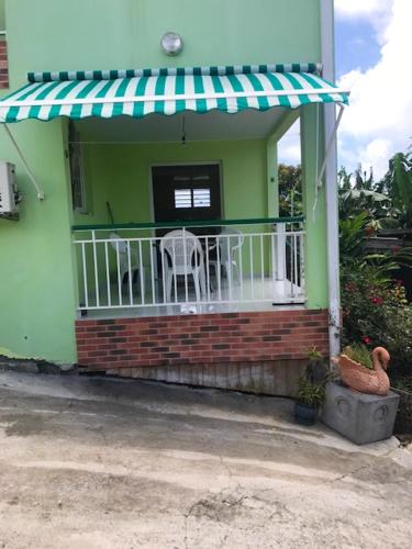 a green house with a balcony with a table and chairs at Appartement avec vue sur la mer à Le Marin, Climatisé, 80 m² in Le Marin