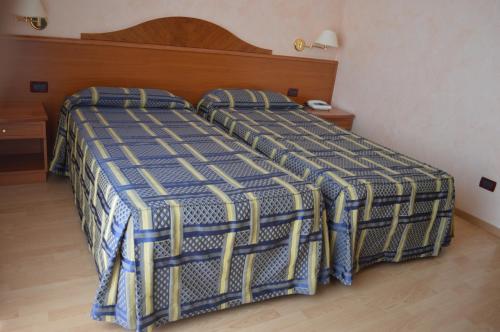 two beds in a hotel room with a blue and white bedspread at Hotel Parco Serrone in Corato