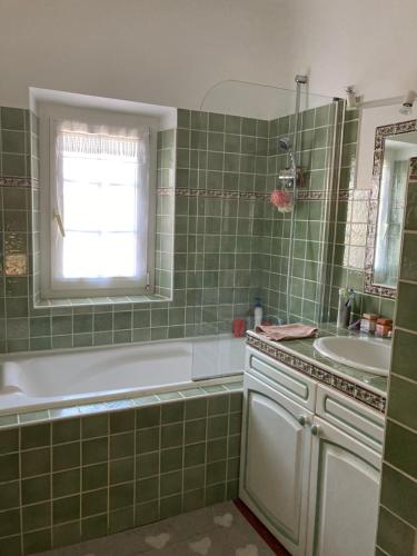 La salle de bains est pourvue de carrelage vert, d'une baignoire et d'un lavabo. dans l'établissement LE MAS, à Aix-en-Provence