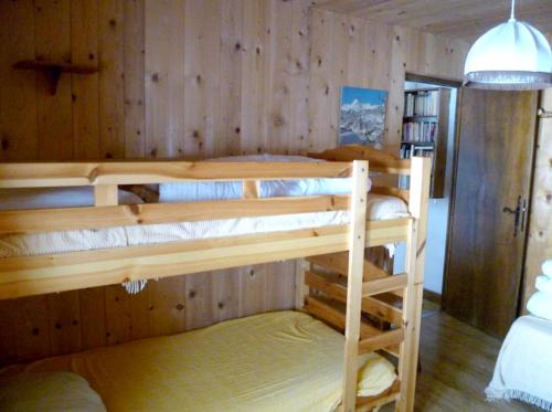 2 łóżka piętrowe w pokoju z drewnianymi ścianami w obiekcie Maison de 2 chambres a Notre Dame de Bellecombe a 100 m des pistes avec jardin amenage et wifi w mieście Notre-Dame-de-Bellecombe