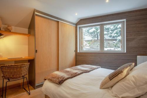 a bedroom with a bed with a window and a chair at Appartement spacieux L'Alpe d'Huez, balcon in LʼHuez