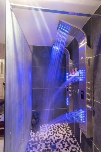 La salle de bains est pourvue d'une douche avec des lumières bleues. dans l'établissement Maison de charme à Arçay avec jacuzzi, à Arçay