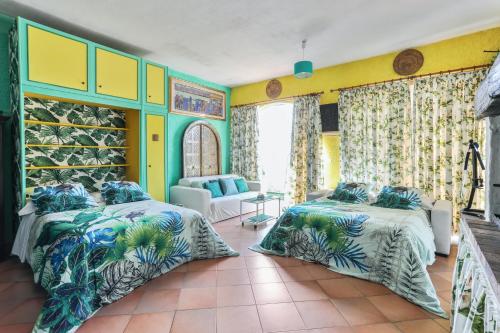 two beds in a room with yellow and green walls at Studio en bord de mer à Menton avec piscine privée 80 m² in Menton