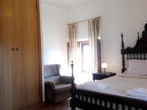 a bedroom with a bed and a chair and a window at Charming house in Alcobaça with mountain view in Alcobaça