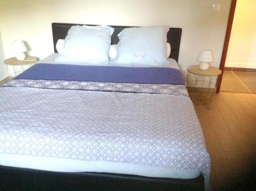 1 dormitorio con 1 cama grande con sábanas y almohadas blancas en Appartement de 2 chambres avec balcon et wifi a Les Abymes a 7 km de la plage, en Les Abymes