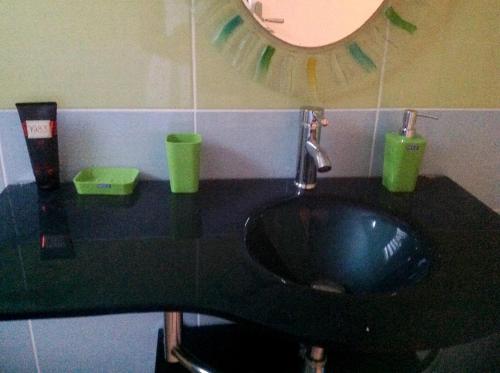 a bathroom with a black sink and green cups at Appartement de 2 chambres avec balcon et wifi a Les Abymes a 7 km de la plage in Les Abymes