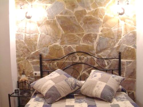 1 cama con 2 almohadas y pared de piedra en 2 bedrooms villa with private pool garden and wifi at La Calzada de Bejar en La Calzada de Béjar