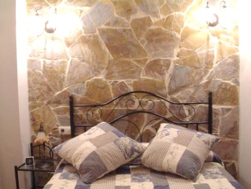 a bed with two pillows and a stone wall at Charming Villa with Private Pool in La Calzada de Béjar in La Calzada de Béjar