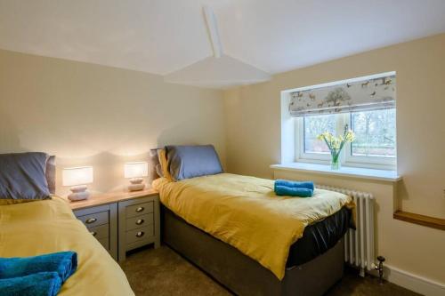 1 dormitorio con 2 camas y ventana en Sloley Hall Cottages - Stable 1 en Tunstead