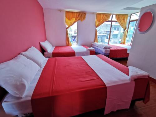 a room with three beds with red and white sheets at La Casa De Mi Sub in Puerto Baquerizo Moreno