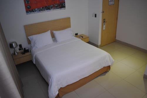 a bedroom with a large bed with white sheets and pillows at Radisson Diamond Barranquilla in Barranquilla