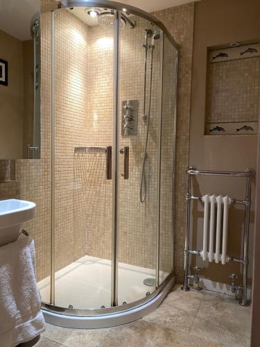 a shower with a glass door in a bathroom at Oriel Cottage, Aldeburgh in Aldeburgh