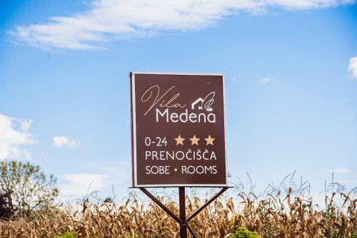 a sign in the middle of a field of grass at Rooms Vila Medena in Brežice