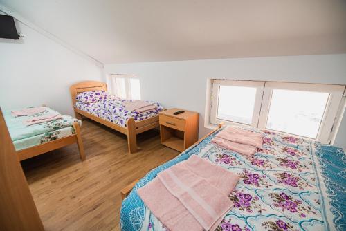 a bedroom with two beds and a table and two windows at Rooms Vila Medena in Brežice