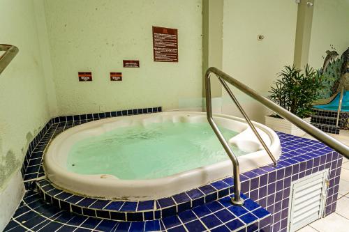 a jacuzzi tub in a bathroom with blue tiles at Apartamento Ingleses Norte in Florianópolis