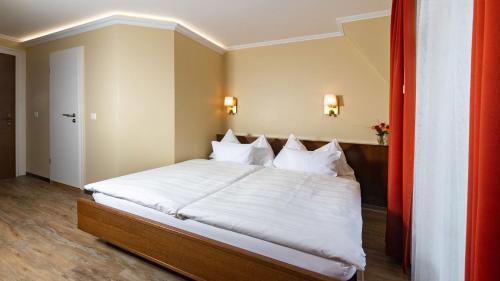 a bedroom with a large bed with white sheets at Swiss Inn & Apartments in Interlaken