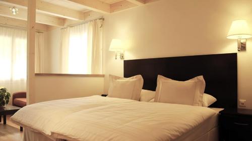 a bedroom with a large white bed with two pillows at Swiss Inn & Apartments in Interlaken