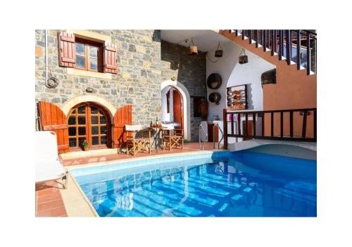 a swimming pool in front of a house at Elounda Traditional Homes of Crete in Elounda