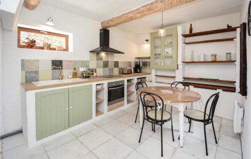 une cuisine avec des armoires vertes, une table et des chaises dans l'établissement Le Mas du Tes, à Saint-Sèbastien