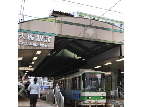 a person walking under an overpass with a train at Hotel Suntargas Otsuka - Vacation STAY 08508v in Tokyo