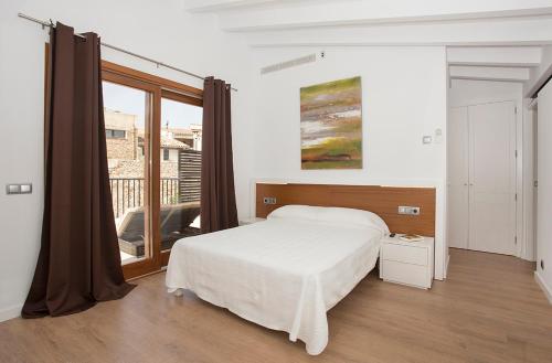 a bedroom with a bed and a large window at ANTIGUA CASA DE PUEBLO SANT SEBASTIA in Pollença