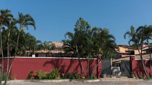 a red fence with palm trees in front of a building at Pousada Tartaruga in Búzios