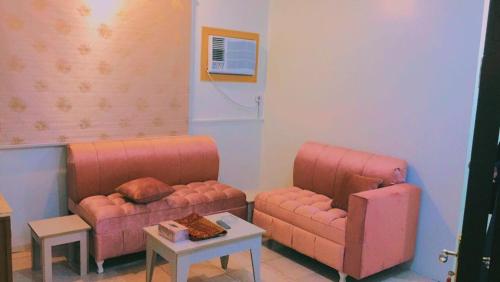 a living room with two pink couches and a table at Al Beagy Furnished Units in Hafr Al Baten