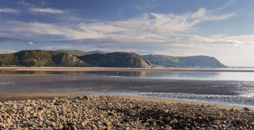 a beach with rocks and mountains in the water at Coastal Gem Apartment by Seaside Llandudno in Llandudno