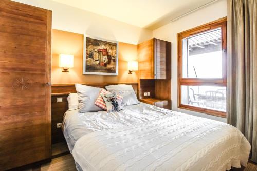 une chambre avec un grand lit blanc avec une fenêtre dans l'établissement 2 Bed Ski in and Ski out Luxury Apt in 5 star Residence, à Flaine