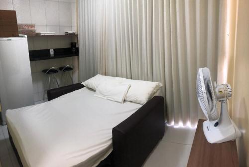 1 dormitorio con 1 cama blanca y ventilador en Flats Manacá Maragogi, en Maragogi